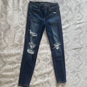 Dark-washed distressed American Eagle next level stretch jeans.